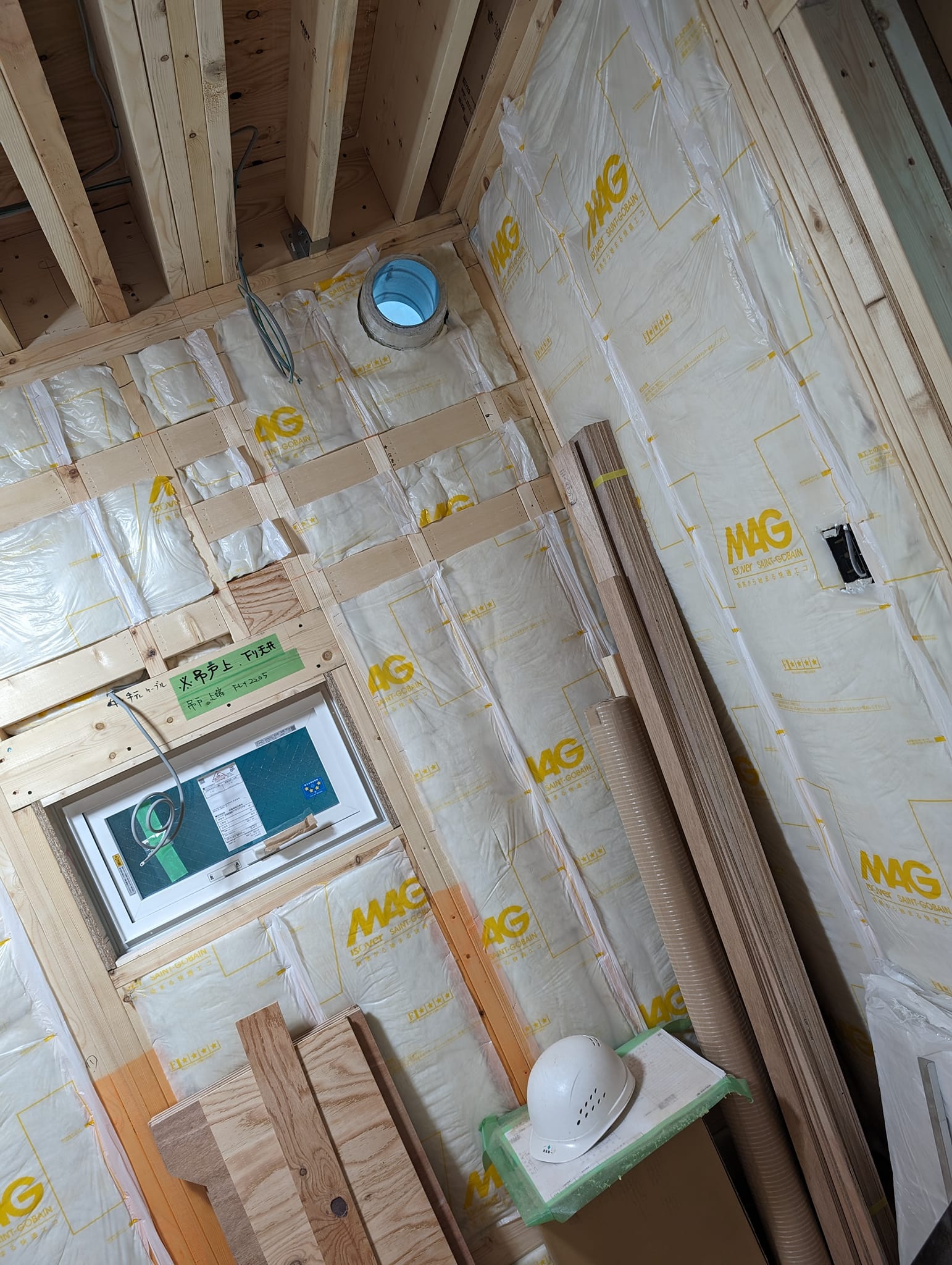 壁に断熱材を敷き詰めている様子。2×4の柱の間に、防湿袋に入ったグラスウールが隙間なく充填されていく