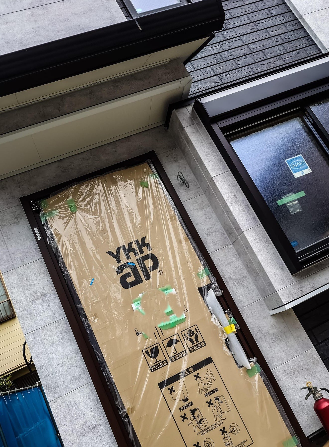 足場解体後の新居の外観。養生されたYKKap社の玄関ドア（ウォールナット色）が見える。この養生が外れれば、さらに映えるはずだ