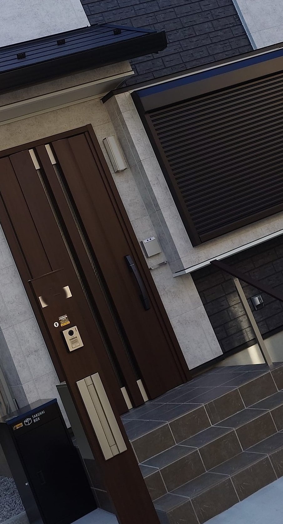 完成した玄関。ケイミュー社のモノトーン系サイディングに、YKKap社のショコラ色の建具を組み合わせた